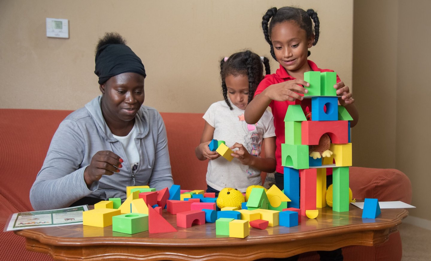 Women and two young girls playing with colorful blocks