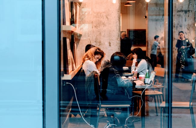 People sitting at tables working in a cafe.