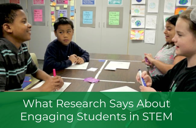 Four students gathered around a classroom table discussing a STEM activity.