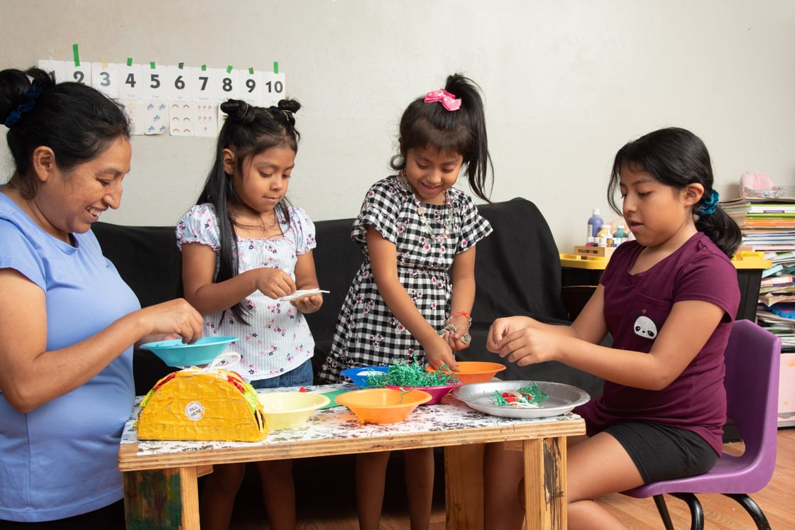 Mother with her three daughters building pretend tacos.